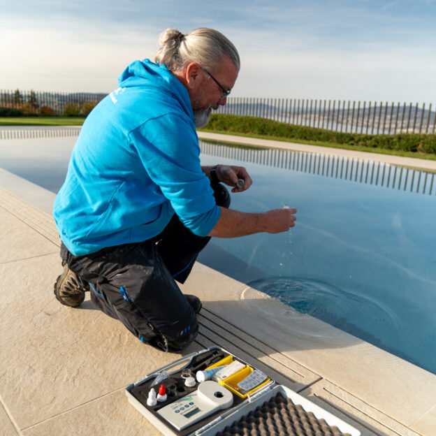 Woodtli-Servicetechniker prüft die Wasserwerte am Beckenrand