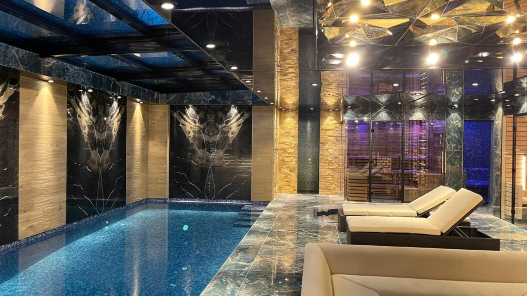 Wellness-Hallenbad mit beleuchteten Wandpaneelen und Sauna