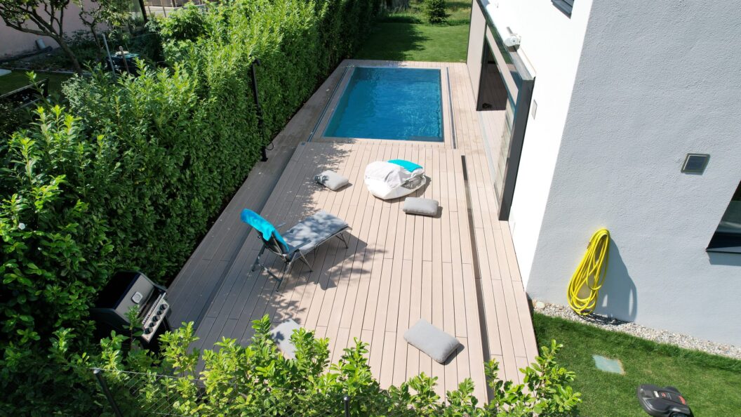 Geschlossenes Schiebedeck aus Holz neben einem schmalen Pool im Garten
