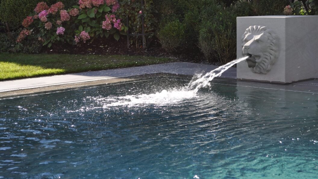 Wasserspeier aus Stein an einem Aussenpool
